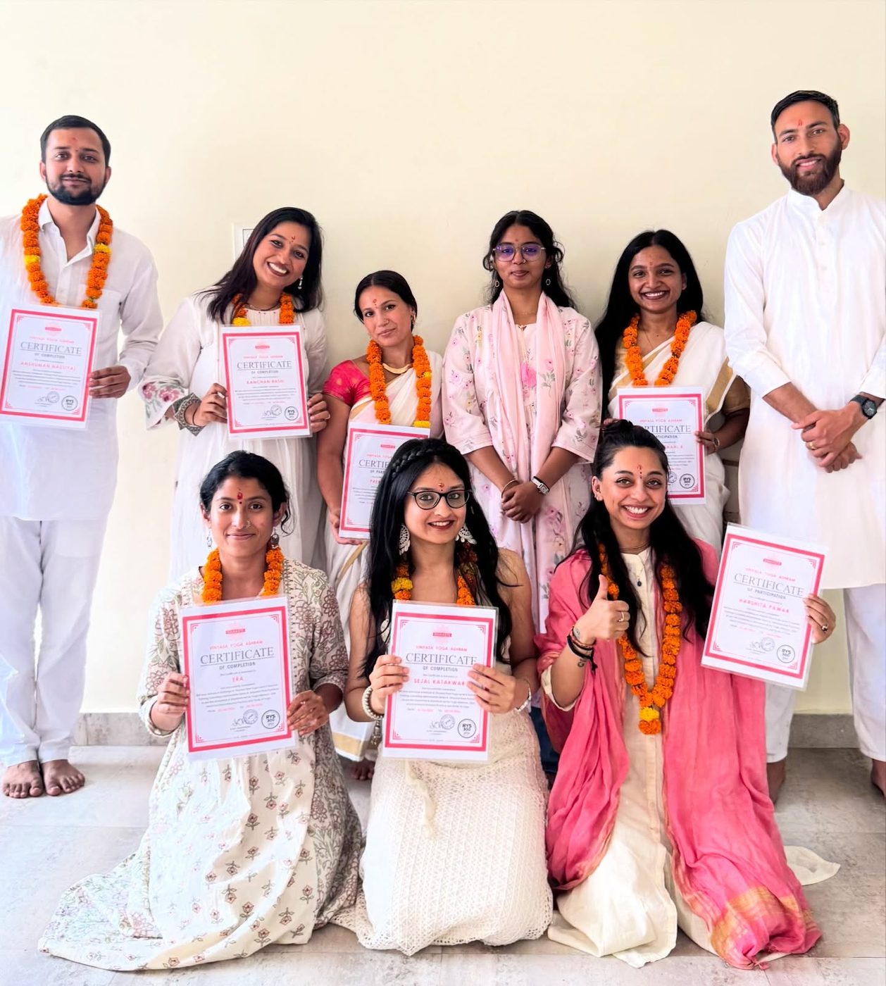 Harshita with her Vinyasa Yoga Ashram graduating cohort, all holding certificates and wearing marigold garlands
