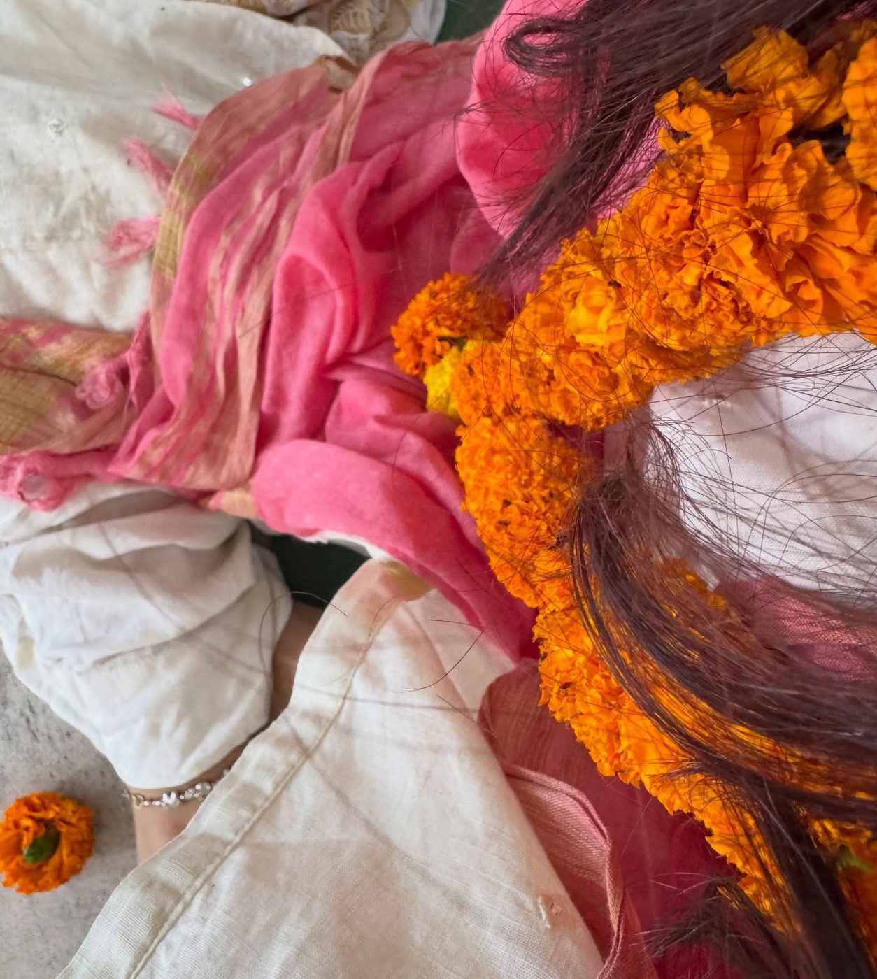 Close-up of a marigold garland over a pink shawl