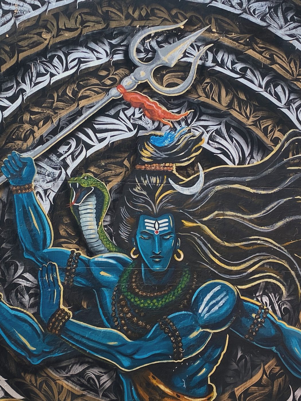 A vivid street mural of Shiva holding a trident